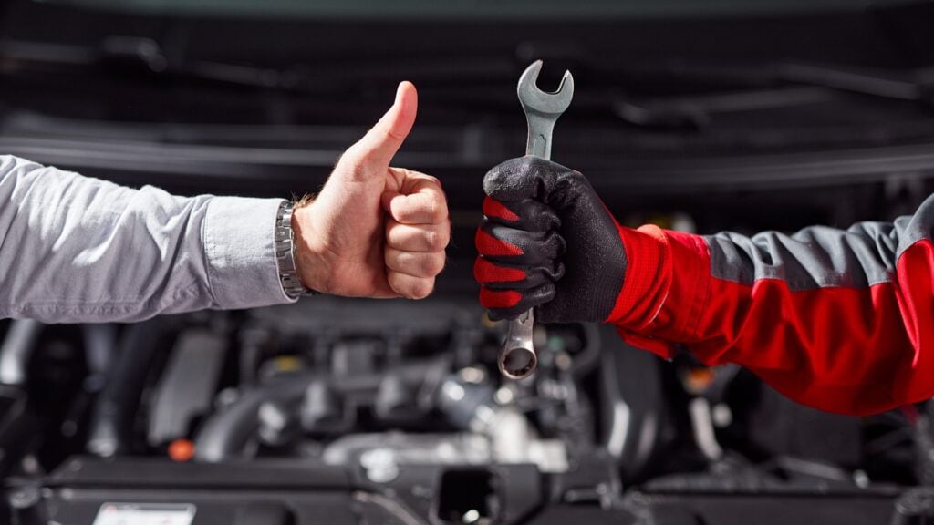 Anonymer Mann, der die Arbeit eines Automechanikers in der Werkstatt abnimmt